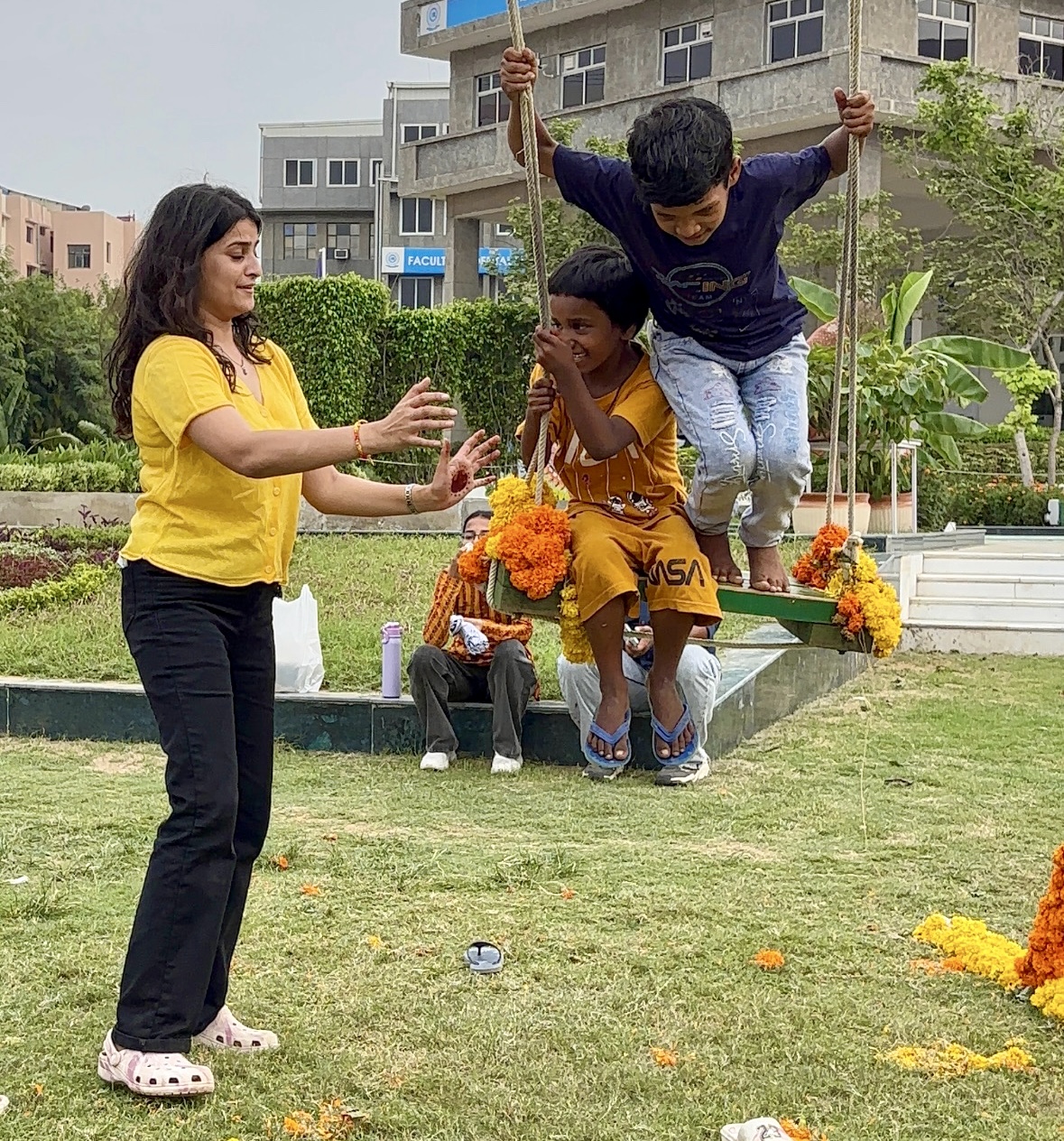 Simran sharing a flower-decorated swing with two children during a Janmashtami celebration